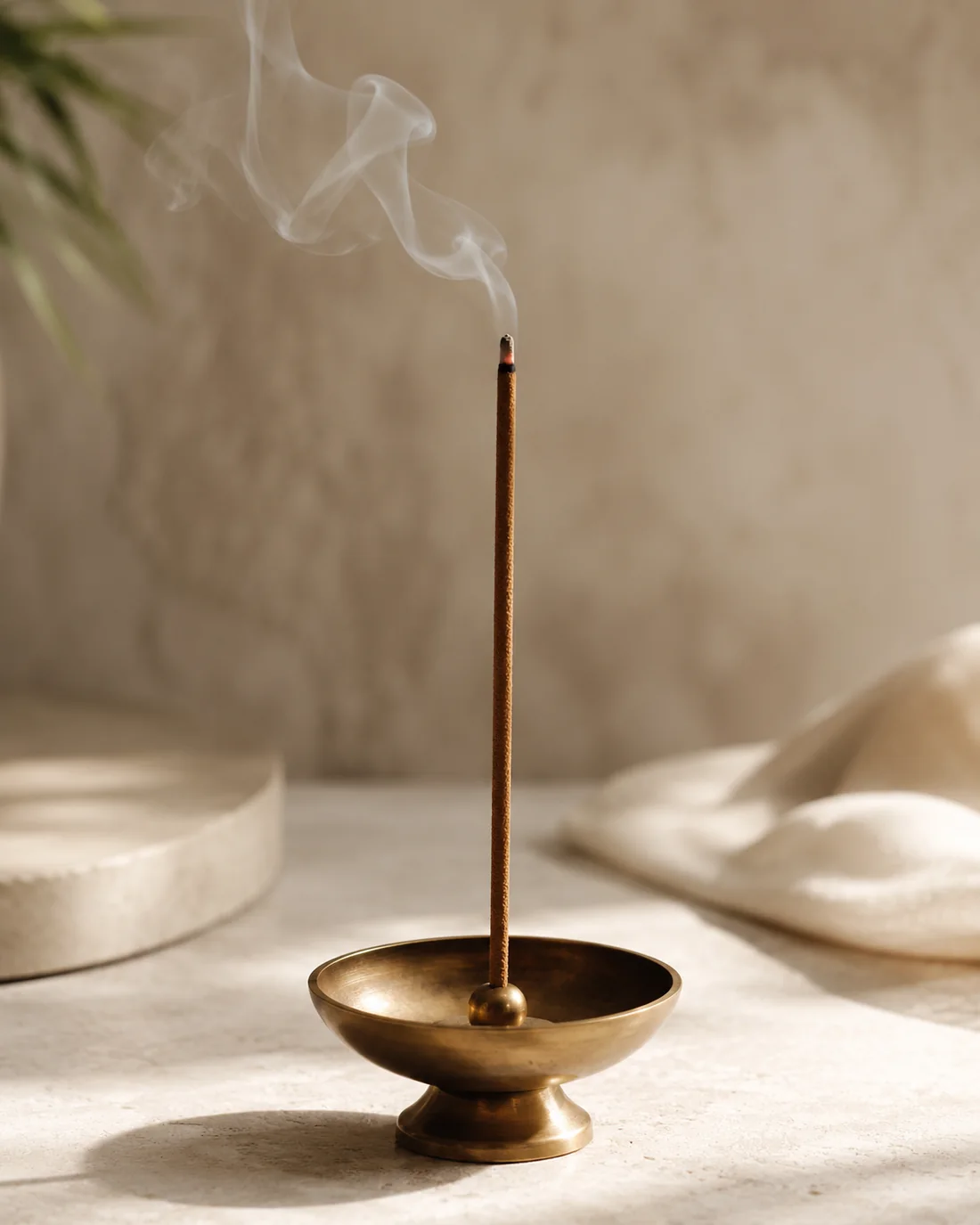 A single brown dhoop stick in a brass holder, in warm natural light
